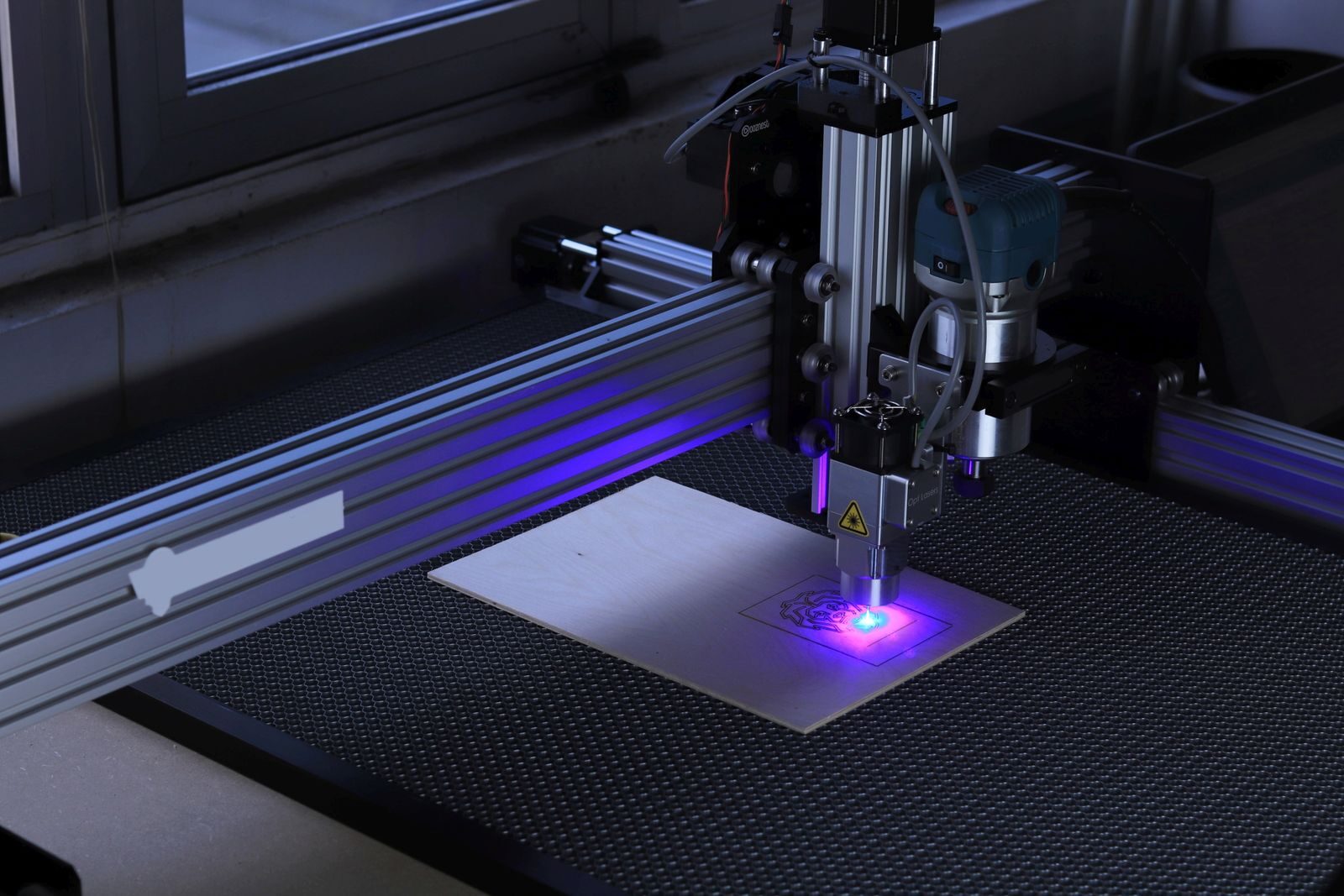 Close-up of a CNC laser engraving machine processing a wooden piece.