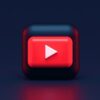 A 3D red play button icon on a dark blue background