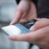 Close-up of hands using a smartphone with a touchscreen, emphasizing mobile technology.
