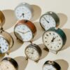 Assorted vintage alarm clocks in warm light showcasing timeless elegance.