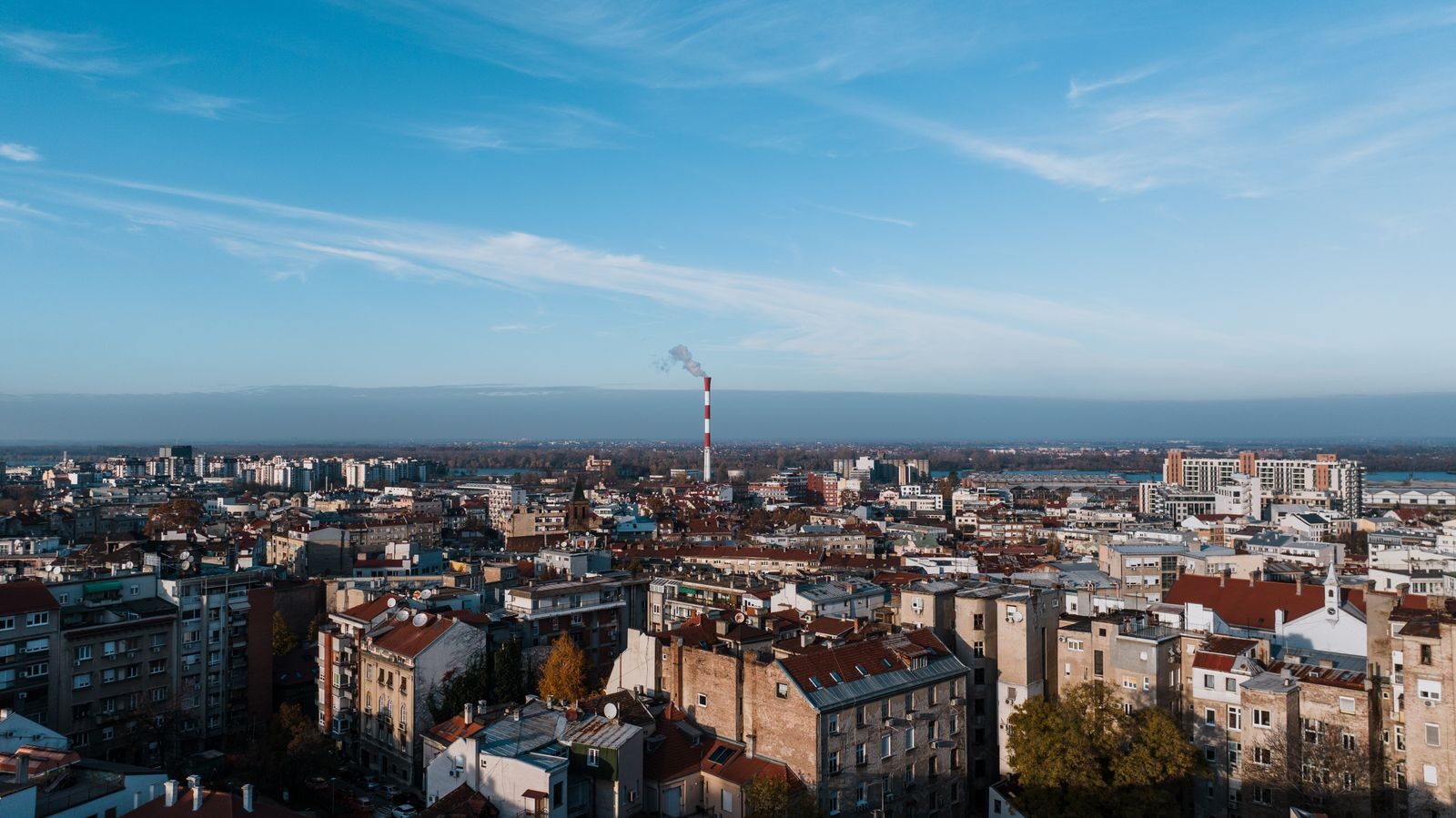 Aerial cityscape of Beograd, Serbia featuring urban skyline and smokestack.