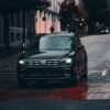 A black Volkswagen car driving on a wet urban street, emphasizing transportation in rainy weather.