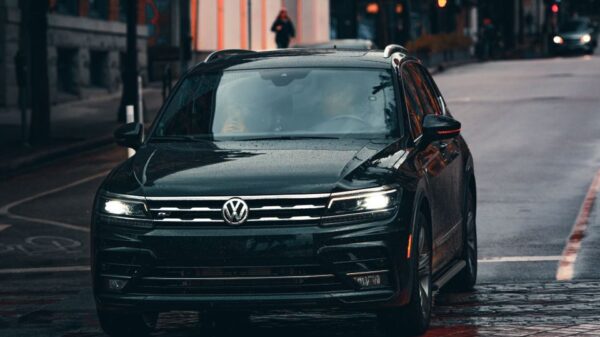 A black Volkswagen car driving on a wet urban street, emphasizing transportation in rainy weather.