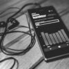Monochrome photo of a smartphone with earphones and audio equalizer on screen.