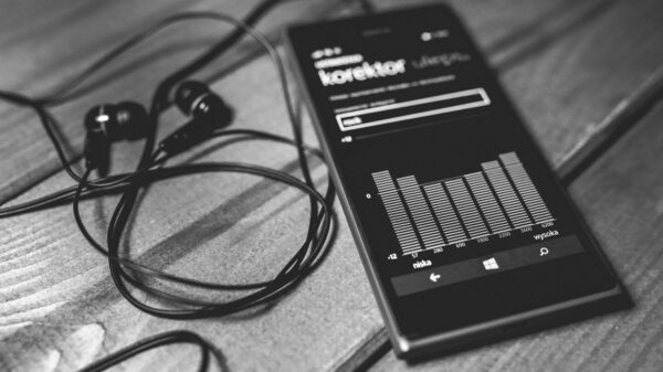 Monochrome photo of a smartphone with earphones and audio equalizer on screen.