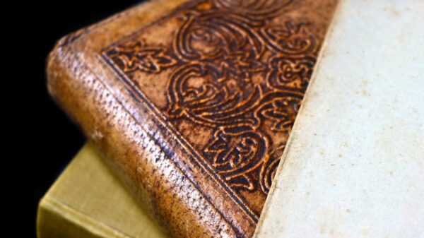 Detailed close-up of an antique leather bound book with ornate engraving and aged paper.