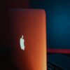 Minimalist laptop design featuring glowing Apple logo with dramatic lighting.