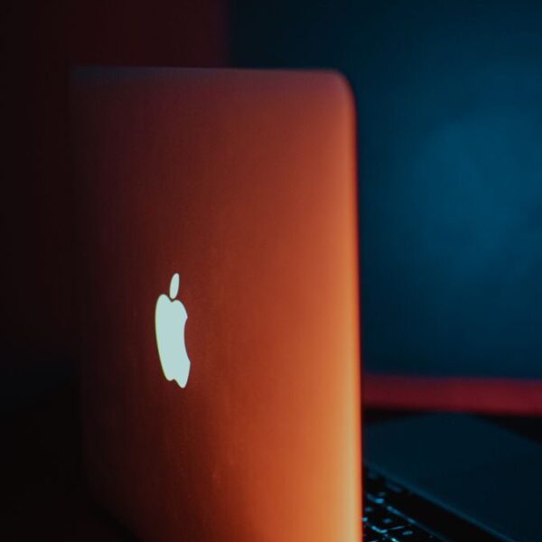 Minimalist laptop design featuring glowing Apple logo with dramatic lighting.