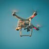 A drone in flight against a clear blue sky, showcasing modern technology.