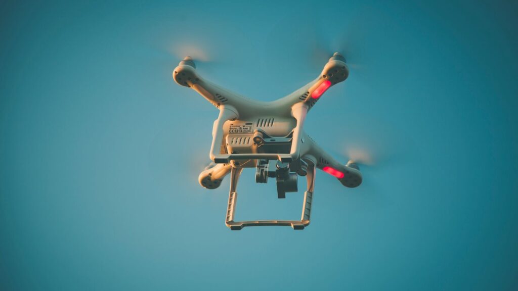 A drone in flight against a clear blue sky, showcasing modern technology.
