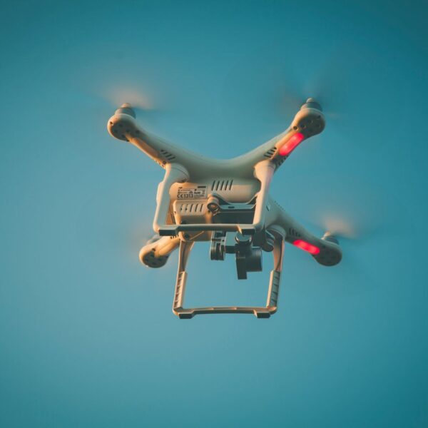 A drone in flight against a clear blue sky, showcasing modern technology.