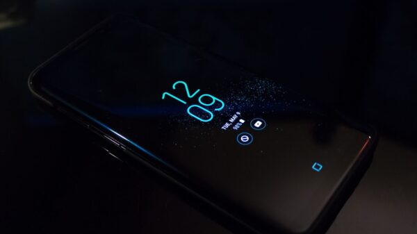 Close-up of a smartphone in the dark displaying digital clock and notifications.