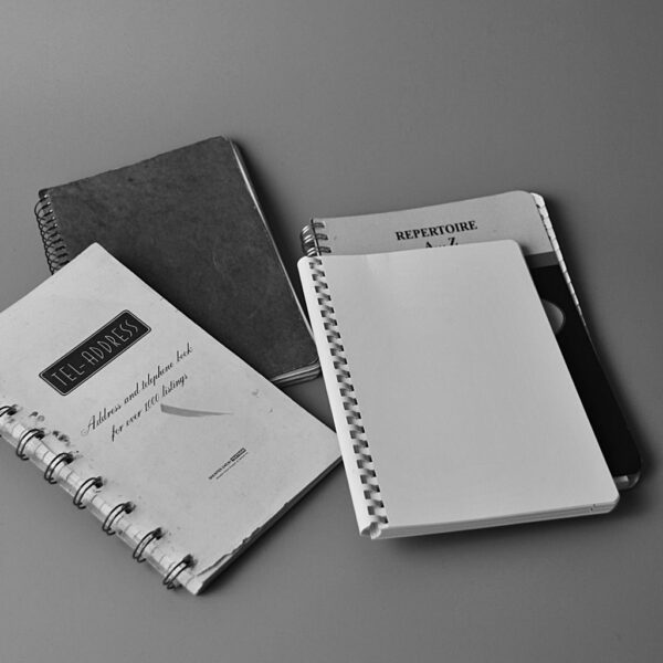 Black and white photo showing spiral notebooks with cover texts in a flat lay setup.