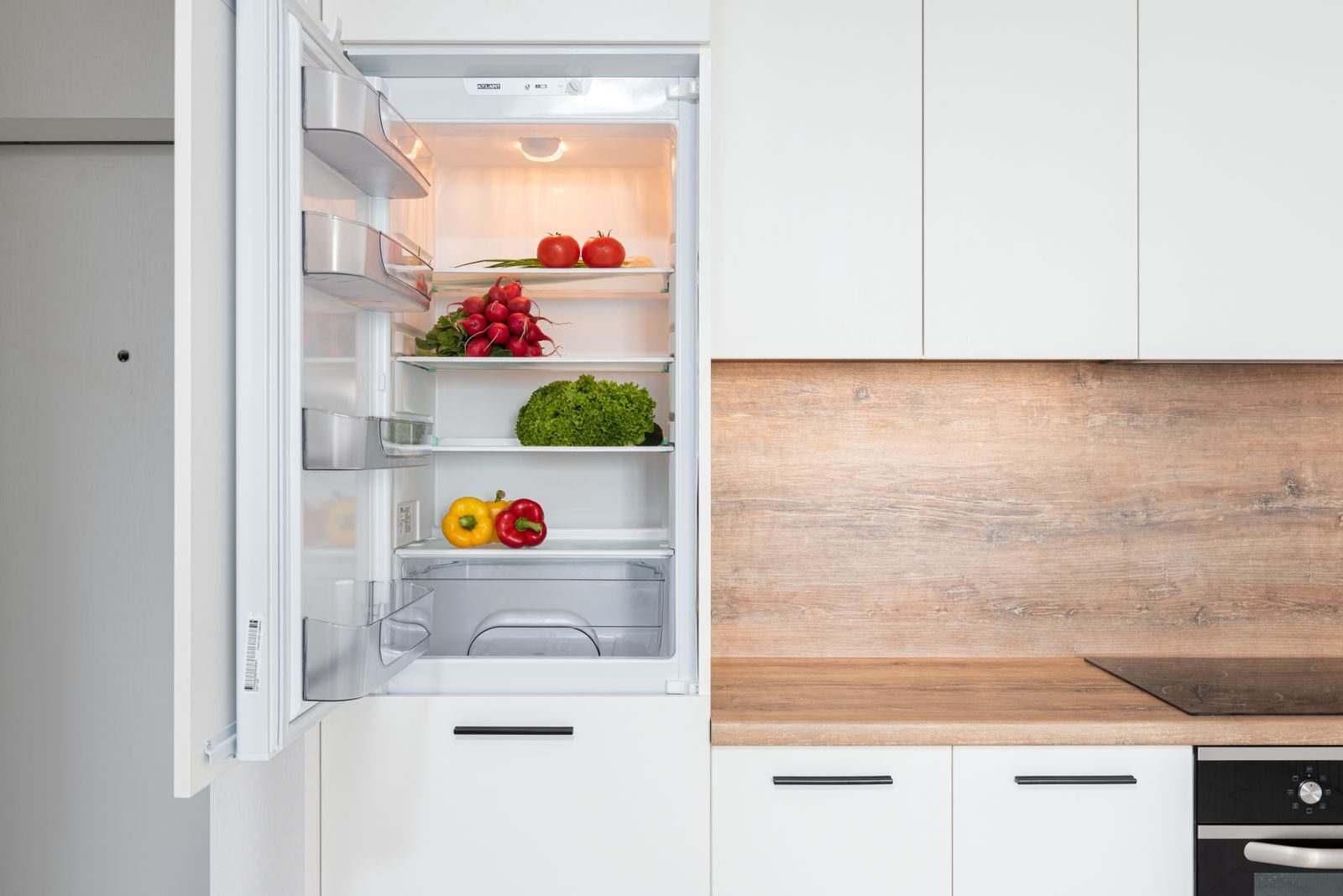 Contemporary kitchen with refrigerator filled with fresh bright tomatoes lettuce and bell peppers