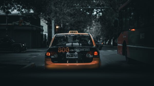 Moody city street with a taxi and bus at night, showcasing urban transportation.