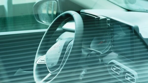 Close-up of a car's dashboard and steering wheel viewed through a tinted window.