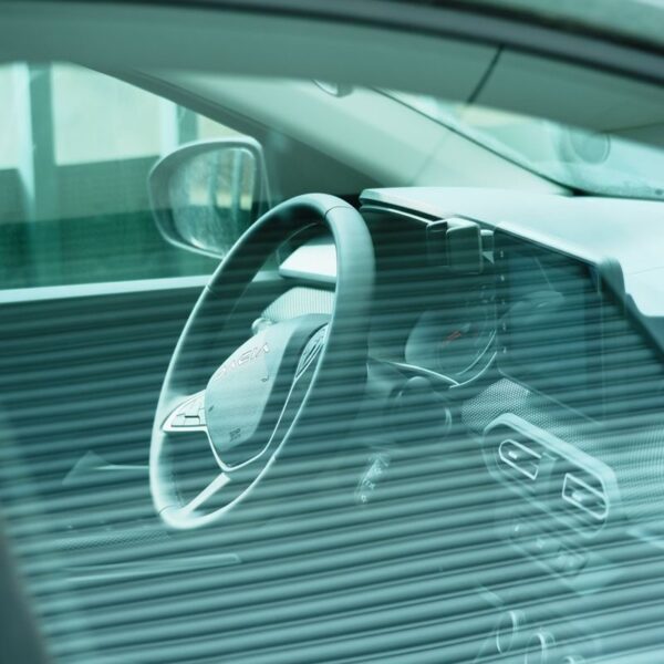 Close-up of a car's dashboard and steering wheel viewed through a tinted window.