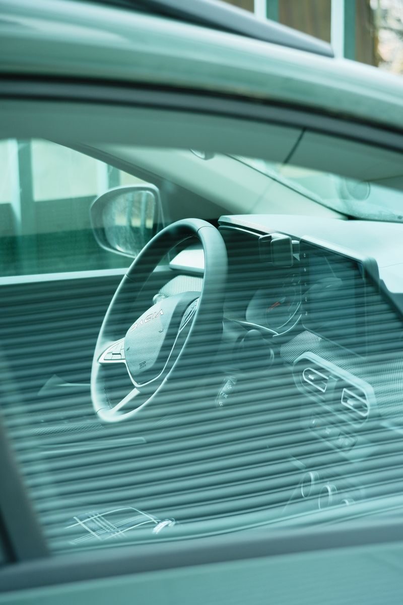 Close-up of a car's dashboard and steering wheel viewed through a tinted window.