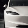 Close-up of a modern white electric car's sleek front design outdoors.