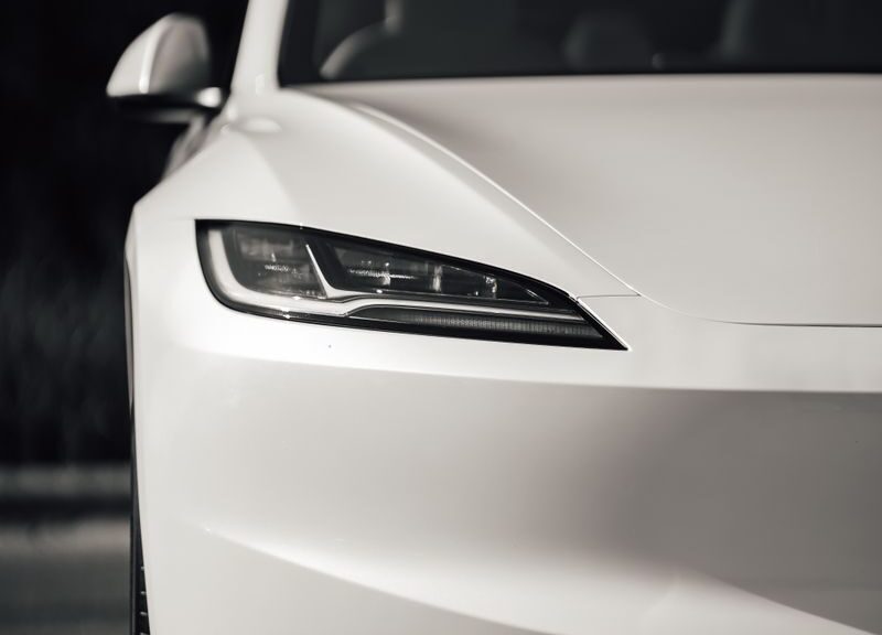 Close-up of a modern white electric car's sleek front design outdoors.