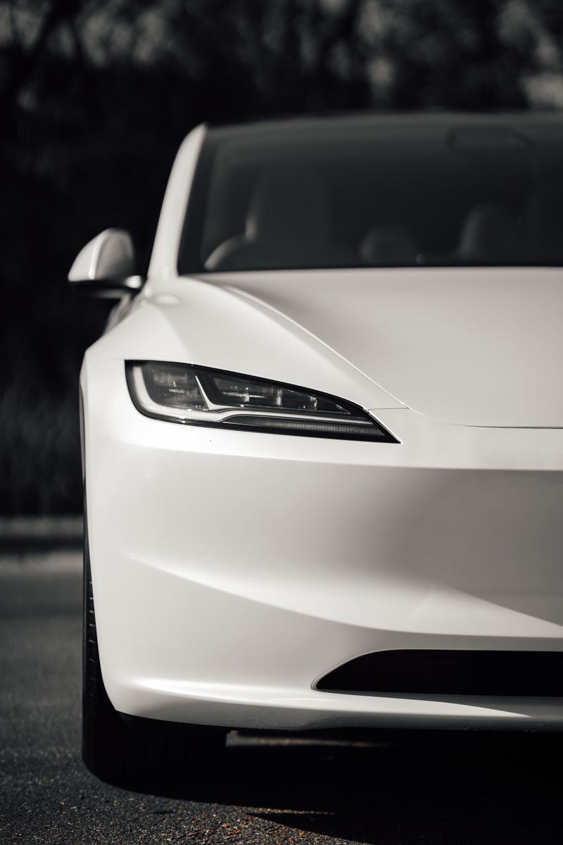Close-up of a modern white electric car's sleek front design outdoors.