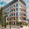 Elegant modern building with balconies and greenery in Tivat, Montenegro, under a clear blue sky.