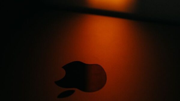 Close-up of an Apple logo with dramatic warm lighting creating a moody atmosphere.