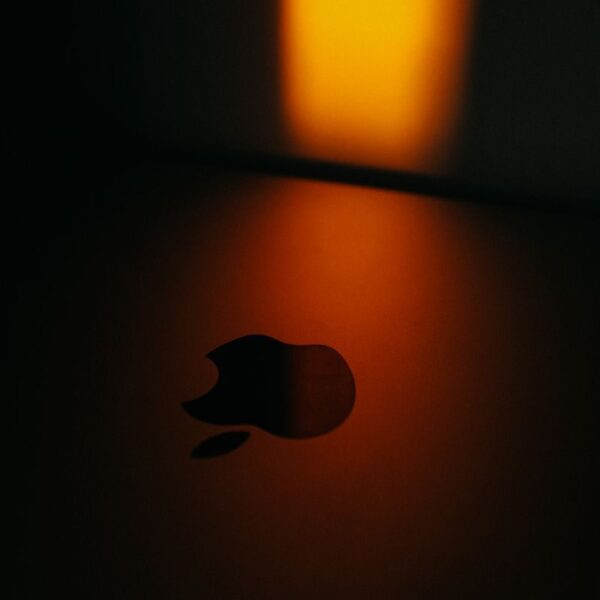 Close-up of an Apple logo with dramatic warm lighting creating a moody atmosphere.