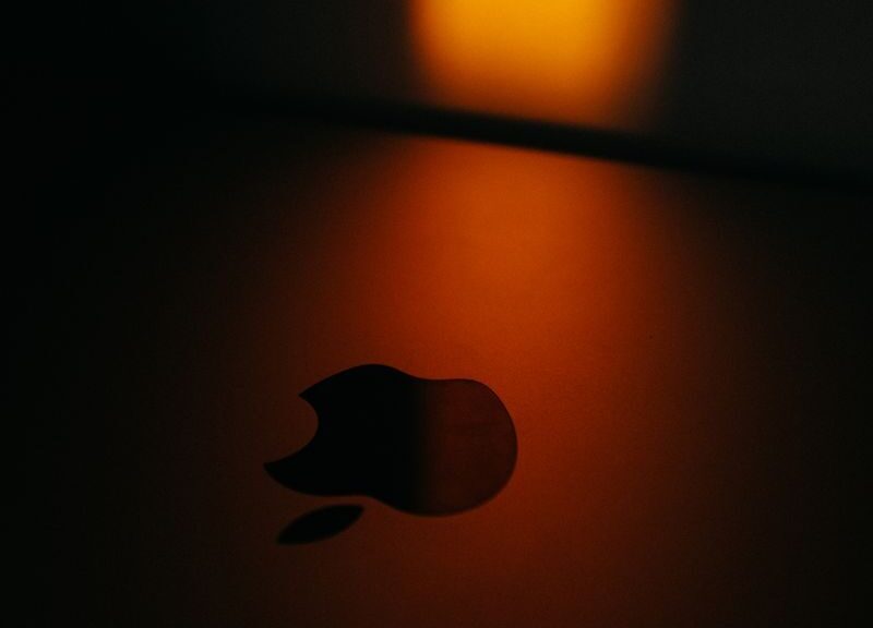 Close-up of an Apple logo with dramatic warm lighting creating a moody atmosphere.