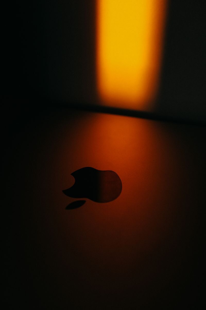 Close-up of an Apple logo with dramatic warm lighting creating a moody atmosphere.