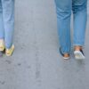 Two people walking casually on a city pavement in jeans and sneakers.