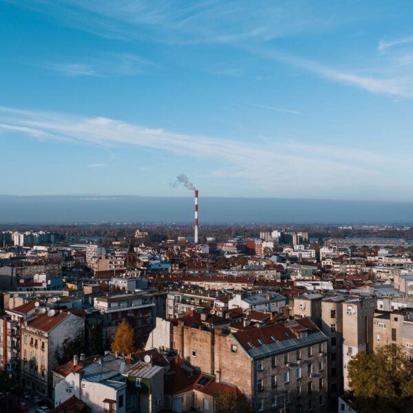 Aerial cityscape of Beograd, Serbia featuring urban skyline and smokestack.