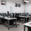 An empty computer lab featuring multiple vacant workstations with modern monitors.