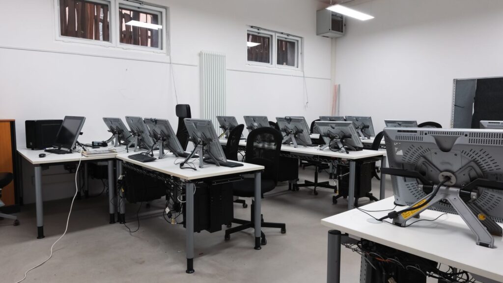 An empty computer lab featuring multiple vacant workstations with modern monitors.