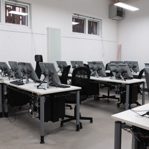 An empty computer lab featuring multiple vacant workstations with modern monitors.