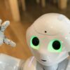 A futuristic humanoid robot with glowing green eyes in a modern setting.