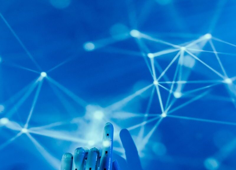 Futuristic robotic hand touching a digital network on a blue background.