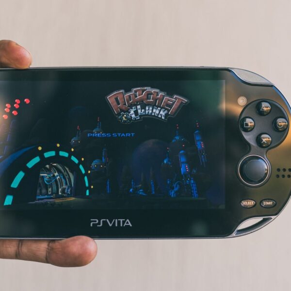 Close-up of a hand holding a PlayStation Vita with Ratchet & Clank displayed on screen. Captured in Johannesburg.