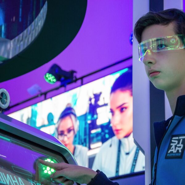Teenager interacts with advanced touchscreen in a vibrant technology exhibition.