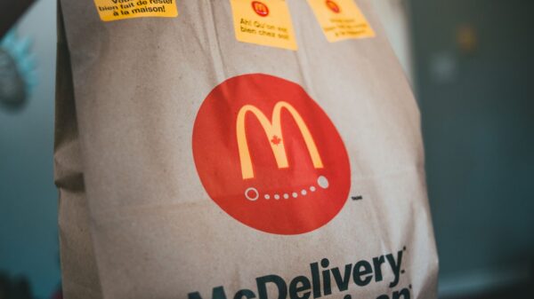Paper packet with tasty fresh hot fast food on blurred background in restaurant