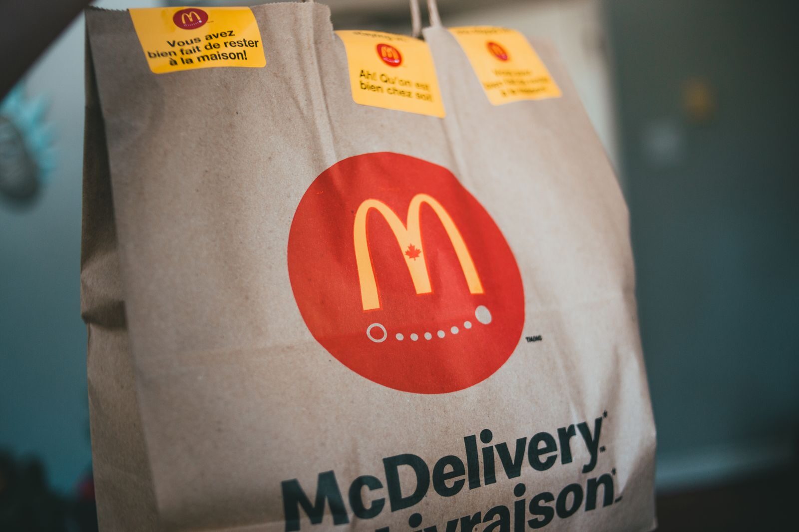 Paper packet with tasty fresh hot fast food on blurred background in restaurant