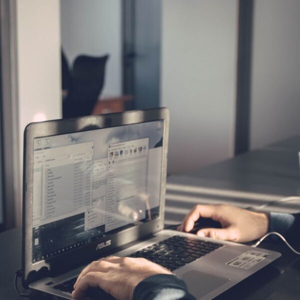 A person typing on a laptop inside an office, emphasizing technology and productivity.