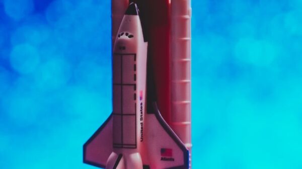 A toy rocket ship launching with vibrant flames against a bright blue bokeh background.