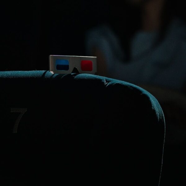 A dimly lit cinema featuring a pair of 3D glasses on a theater seat, capturing an immersive movie-going experience.