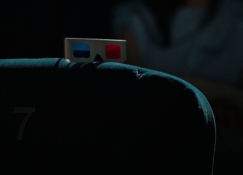 A dimly lit cinema featuring a pair of 3D glasses on a theater seat, capturing an immersive movie-going experience.