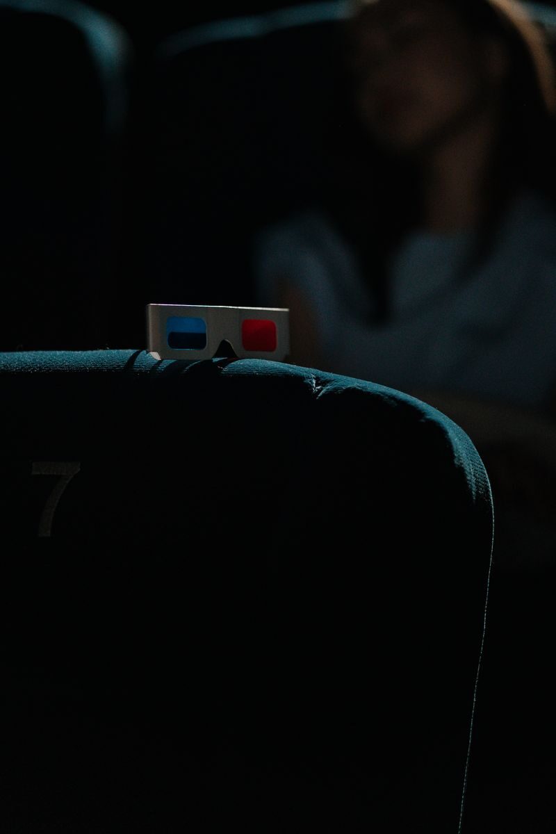 A dimly lit cinema featuring a pair of 3D glasses on a theater seat, capturing an immersive movie-going experience.