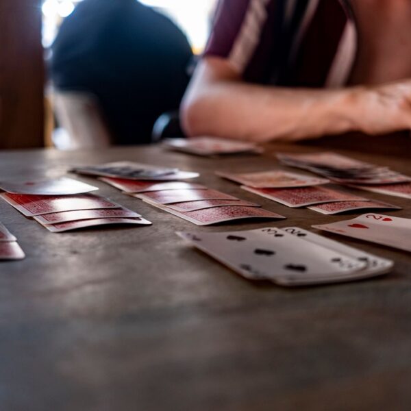 Intimate tabletop scene of people playing cards with a focus on hands and playing cards.