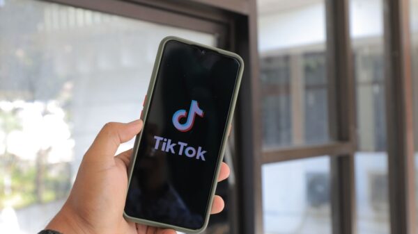 Close-up of a hand holding a smartphone displaying the TikTok app indoors.