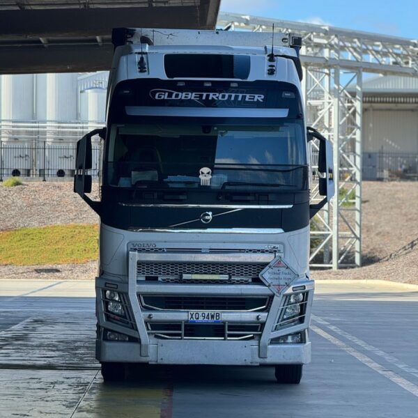 White Globetrotter semi-trailer truck parked outdoors under partial shade.