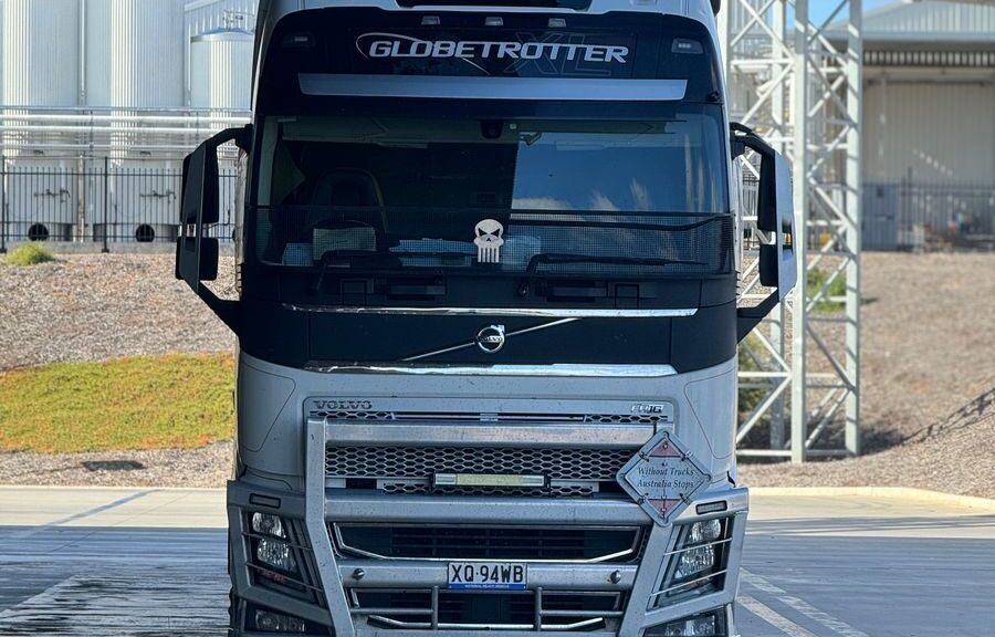 White Globetrotter semi-trailer truck parked outdoors under partial shade.